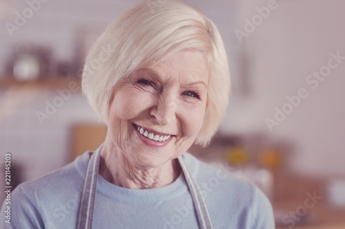 Be happy. Joyful senior gay woman being in the bright room looking straight and smiling.