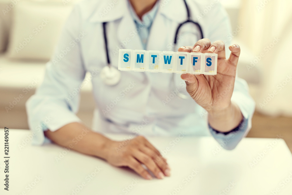 You should try this. Selective focus on a plastic box for medication held by a female doctor sitting at a table and demonstrating the box. You should try this. Selective focus on a plastic box for medication held by a female doctor sitting at a table and demonstrating the box.
