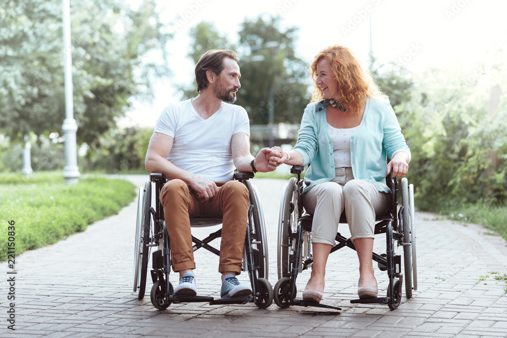Love is in the air. Full length shot of a beautiful couple sitting in their wheelchairs and looking at each other with eyes full of love while holding hands together.