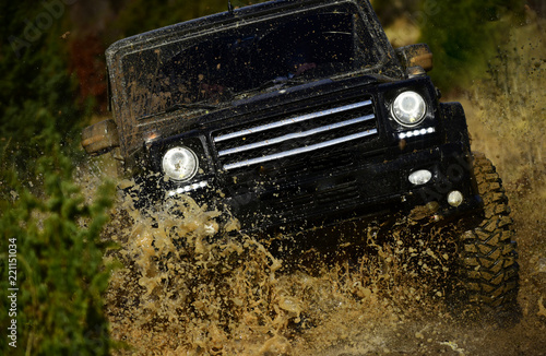 Competition, energy and motorsport concept. Off road vehicle or SUV crossing puddle with dirt splash. Car racing in autumn forest. Auto racing on fall nature background