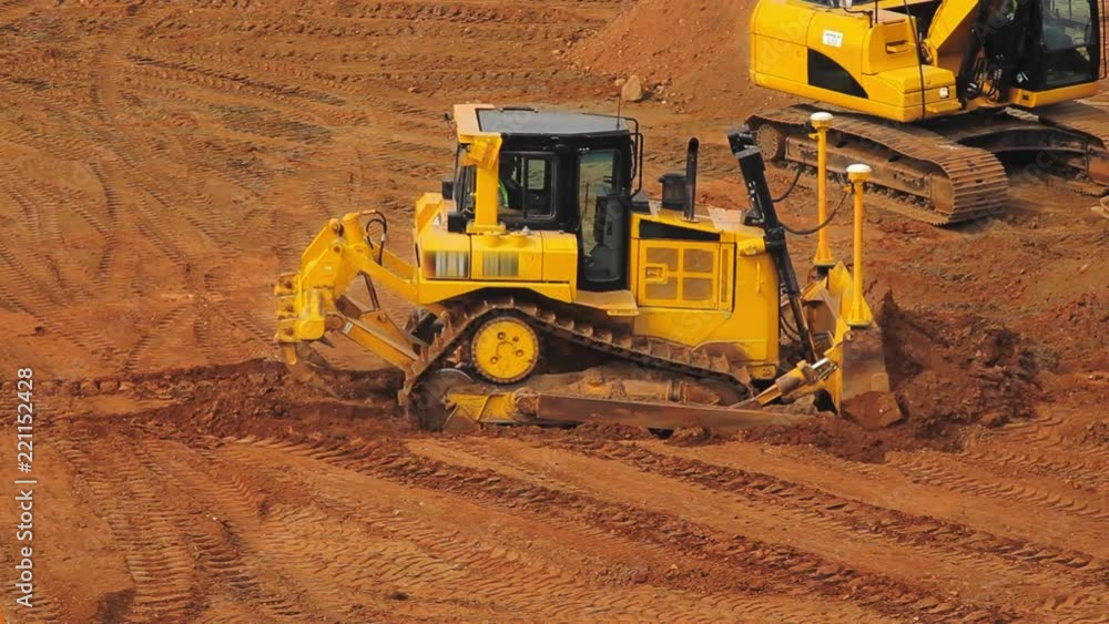 Yellow crawler bulldozer in mining quarry. Heavy machinery in mining industry. Excavator moving soil. Earth moving equipment working at quarry. Preparing building area for road construction Yellow crawler bulldozer in mining quarry. Heavy machinery in mining industry. Excavator moving soil. Earth moving equipment working at quarry. Preparing building area for road construction