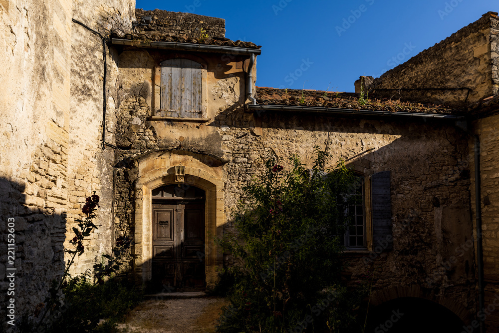 beautiful old stone building with wooden doors and shutters at sunny day, provence, france