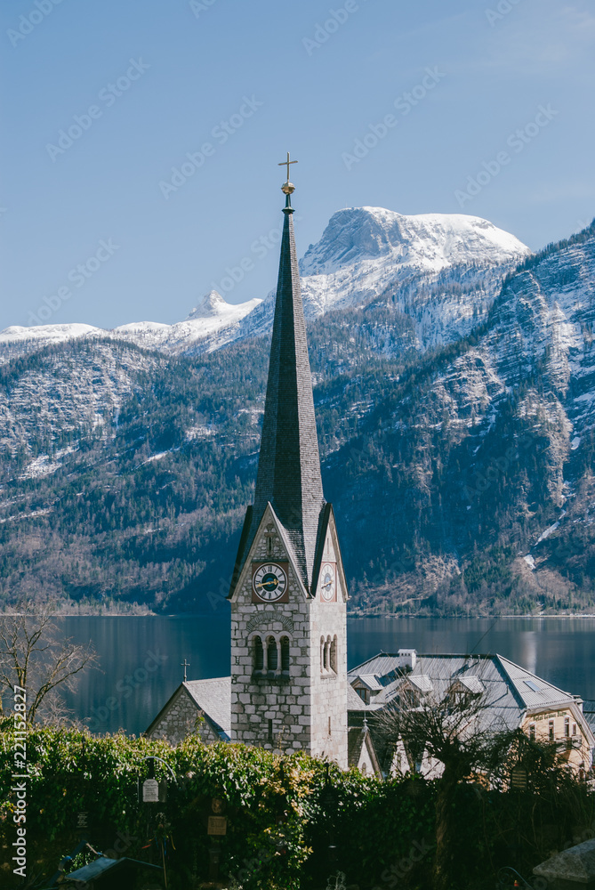 Belfry of the church against white mountains. Hallstatt village in Austria