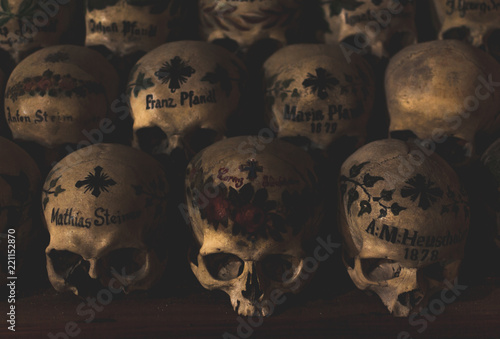Painted skulls in the Parish Church of Hallstatt. Multiple skulls covered with spider web and dust in the ossuary