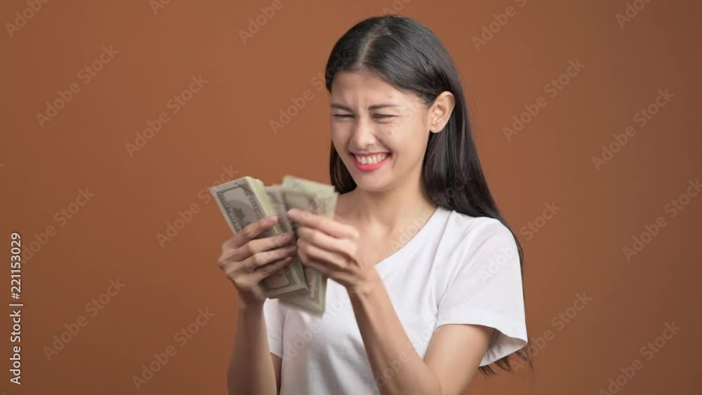 Woman counting cash isolated. Asian woman in white t-shirt counting dollar. Rich woman concept. Woman counting cash isolated. Asian woman in white t-shirt counting dollar. Rich woman concept.