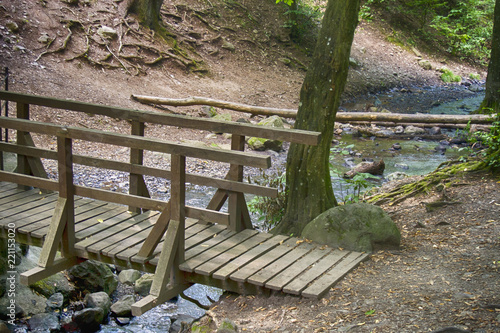 Foto Wooden bridge over the river at the bottom of the mountain