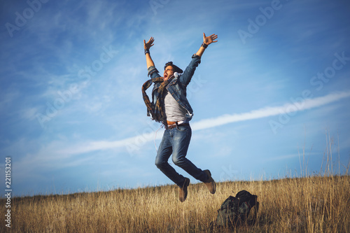 Young happy man jumping into the air in the meadow