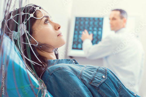 Hoping for better. Side view on a worried young lady looking into vacancy and thinking while undergoing an electroencephalography procedure at a laboratory.