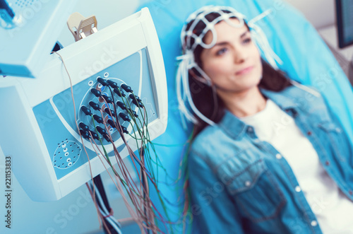 Innovative approach. Selective focus on an electroencephalography machine with node with a brunette lady getting her brain analyzed at a lab. photo