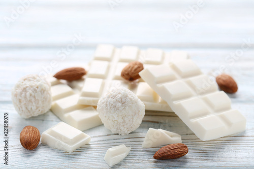 Chocolate pieces with coconut candies and almonds on wooden table