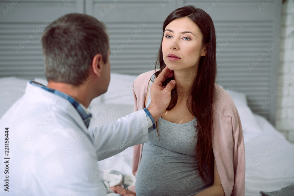 Medical checkup. Smart professional male doctor looking at his patient and checking her pulse while doing medical checkup Medical checkup. Smart professional male doctor looking at his patient and checking her pulse while doing medical checkup