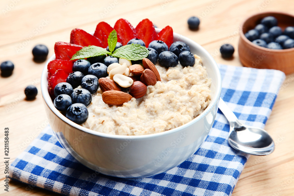 Oatmeal with berries and nuts in bowl on wooden table Oatmeal with berries and nuts in bowl on wooden table