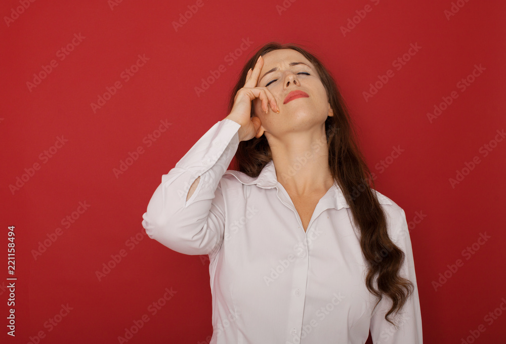 A businesswoman with a headache holding head, isolated on red background A businesswoman with a headache holding head, isolated on red background