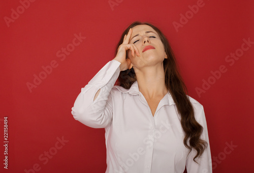 A businesswoman with a headache holding head, isolated on red background
