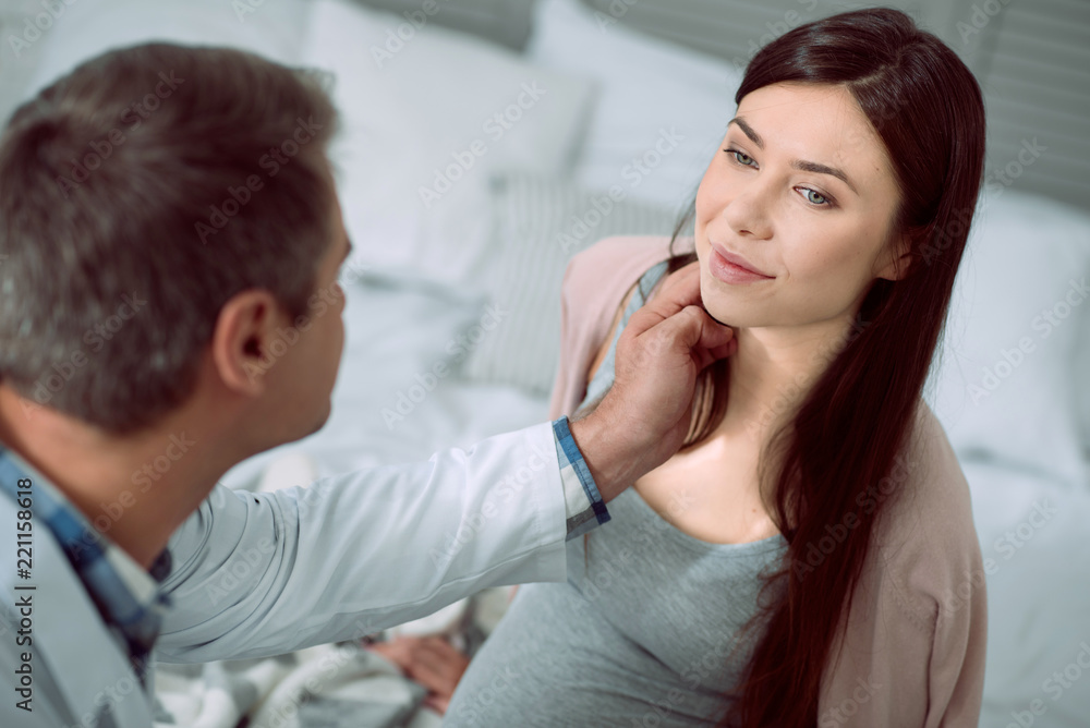 Caring about health. Positive good looking young woman smiling and looking at her doctor while having a medical checkup Caring about health. Positive good looking young woman smiling and looking at her doctor while having a medical checkup