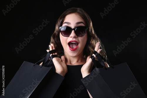 Happy woman with shopping bags on black background