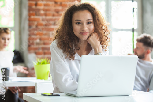 Portrait of cheerful business African-American lady working on laptop.