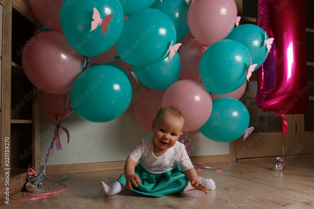 Obraz premium little girl in blue and white dress next to balloons, smiling, holiday, year, birthday child. sits on the floor