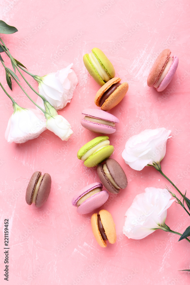 Colorful macarons with eustoma flowers on pink background