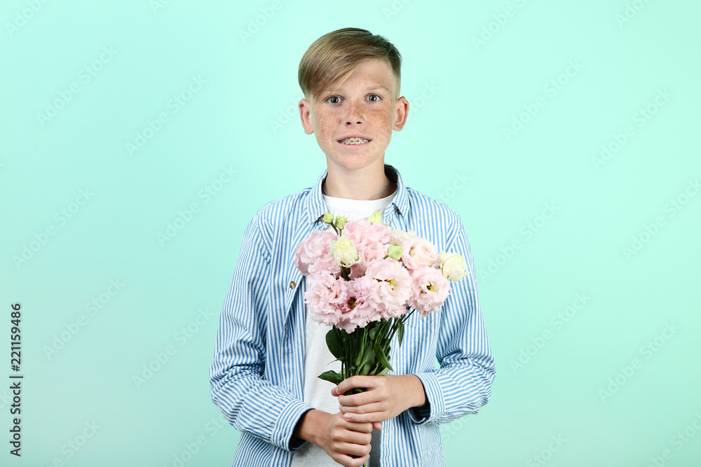Beautiful young boy with eustoma flowers on mint background Beautiful young boy with eustoma flowers on mint background