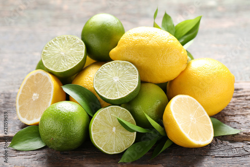 Photo Lemons and limes with green leafs on grey wooden table