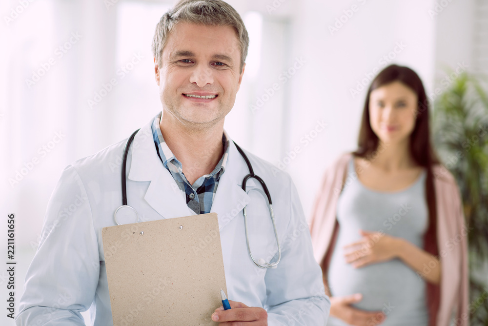 True specialist. Professional handsome smart doctor holding his notes and smiling while working in the hospital True specialist. Professional handsome smart doctor holding his notes and smiling while working in the hospital