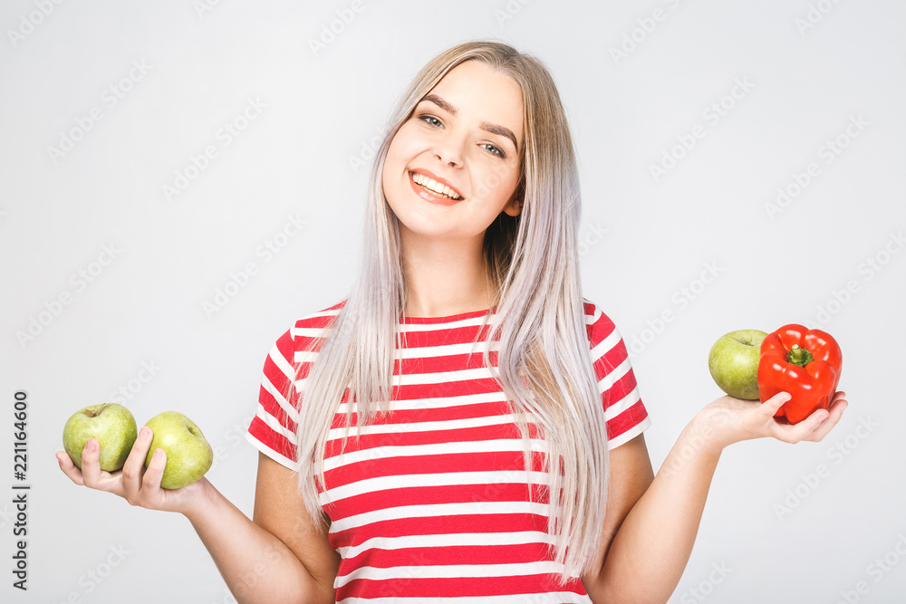 Smiling beautiful blonde woman holding vegan food ingredients. Isolated portrait on white.