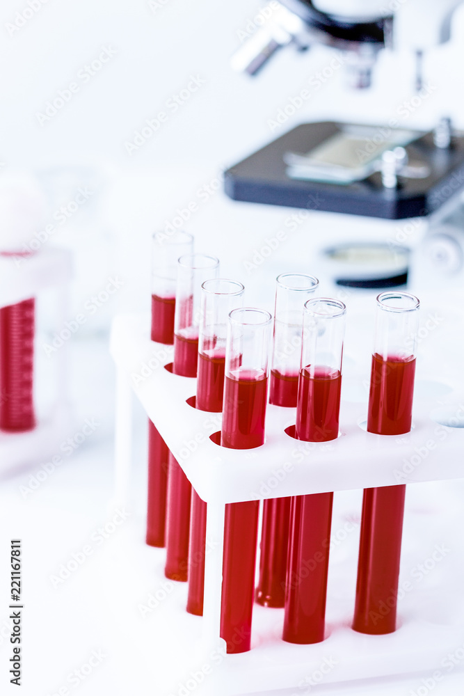blood in glass tubes on background of microscope blood in glass tubes on background of microscope