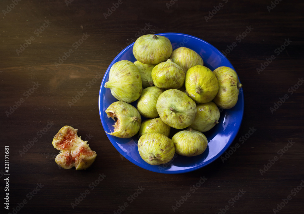 Green figs fruits on blue dish, bitten fruit, flat lay Green figs fruits on blue dish, bitten fruit, flat lay