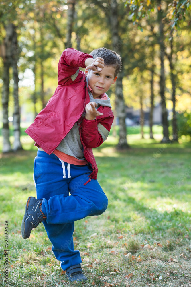 Fototapeta premium Impulsive Caucasian boy yelling and posing in park at autumn, full length portrait