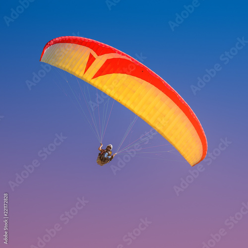 Beautiful yellow and red paraglider flying in colorful sky
