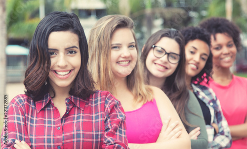 Laughing arabic young adult woman with international girls standing in line