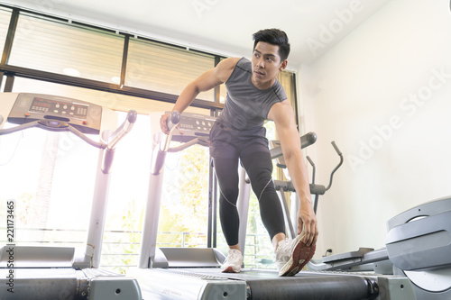 Young handsome man stretching hands in fitness club. Cardio workout, guy warming up, preparing for running on treadmill. Healthy lifestyle, guy training in gym, copy space