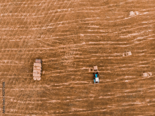Aerial view drone of harvest field with tractor moving hay bale
