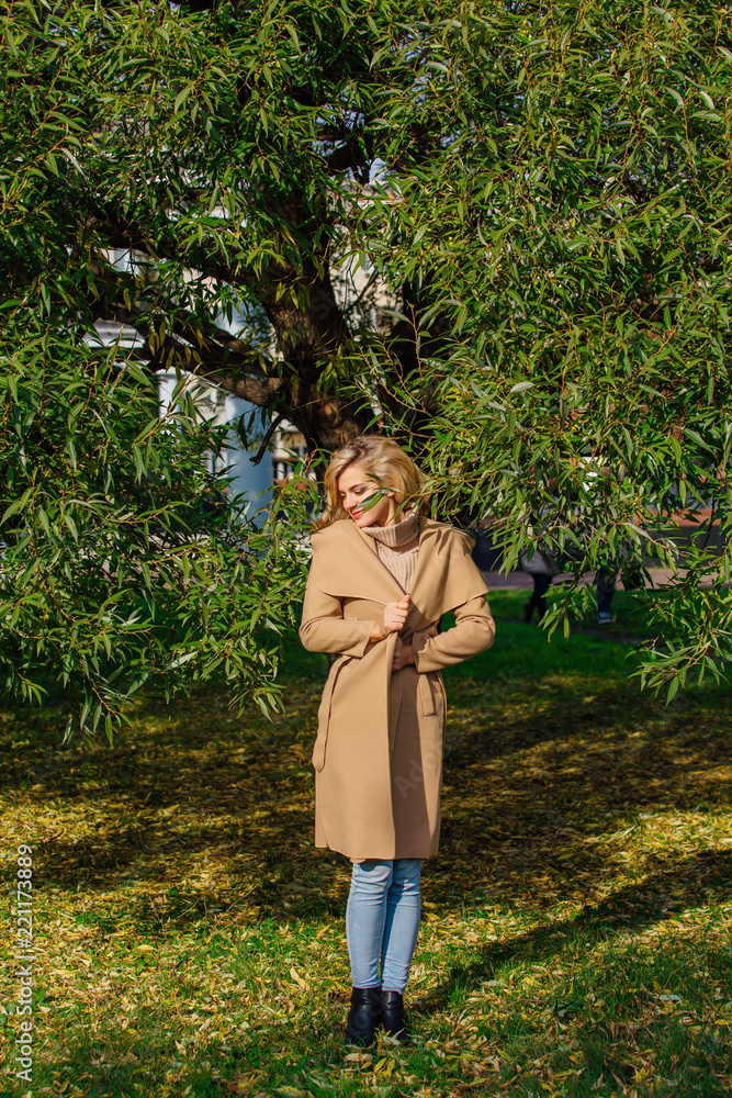 Beautiful elegant woman standing under the tree in autumn park Beautiful elegant woman standing under the tree in autumn park