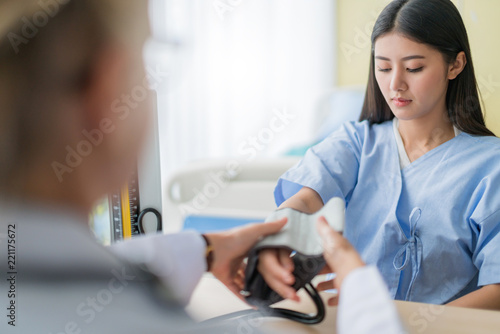 Fototapeta Naklejka Na Ścianę i Meble -  health ideas concept with close up Doctor hand  using sphygmomanometer with stethoscope checking blood pressurefor asian woman patient in the hospital background