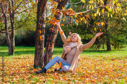 Young beautiful woman throwing up fallen autumn leaves over her head