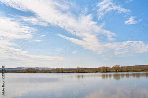 Lake with beautiful clouds and forest on a sunny day.