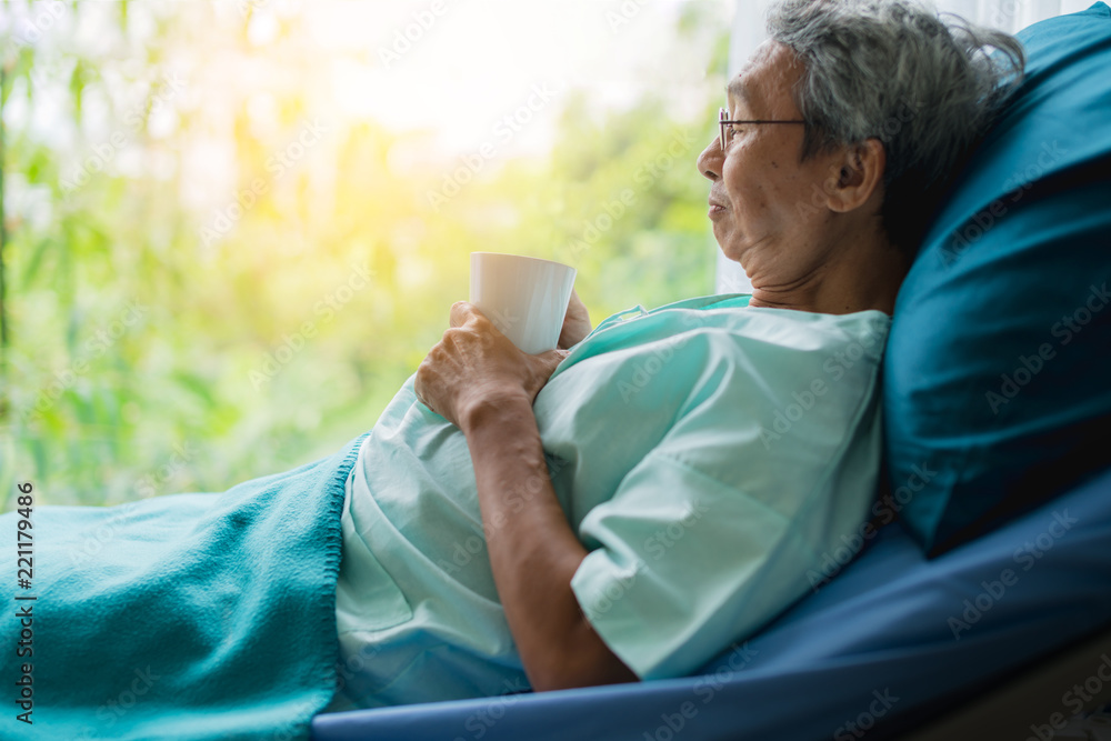 asian senior patient man take a rest with hot tea on hospital bed health ideas concept asian senior patient man take a rest with hot tea on hospital bed health ideas concept