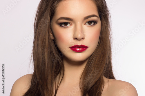 Close up portrait of a beautiful young female face with red lips and long brown hair. Classic make smoky shadows. Extremely long eyelashes and thick eyebrows. Cosmetology, spa, eyesight, injections