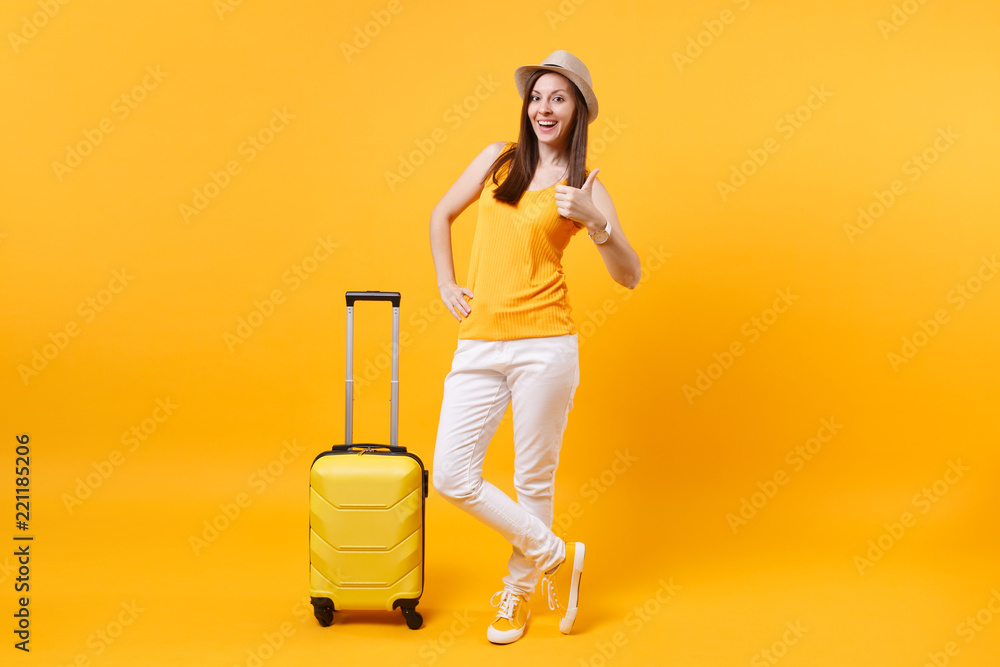 Traveler tourist woman in summer casual clothes, hat with suitcase isolated on yellow orange background. Female passenger traveling abroad to travel on weekends getaway. Air flight journey concept. Traveler tourist woman in summer casual clothes, hat with suitcase isolated on yellow orange background. Female passenger traveling abroad to travel on weekends getaway. Air flight journey concept.