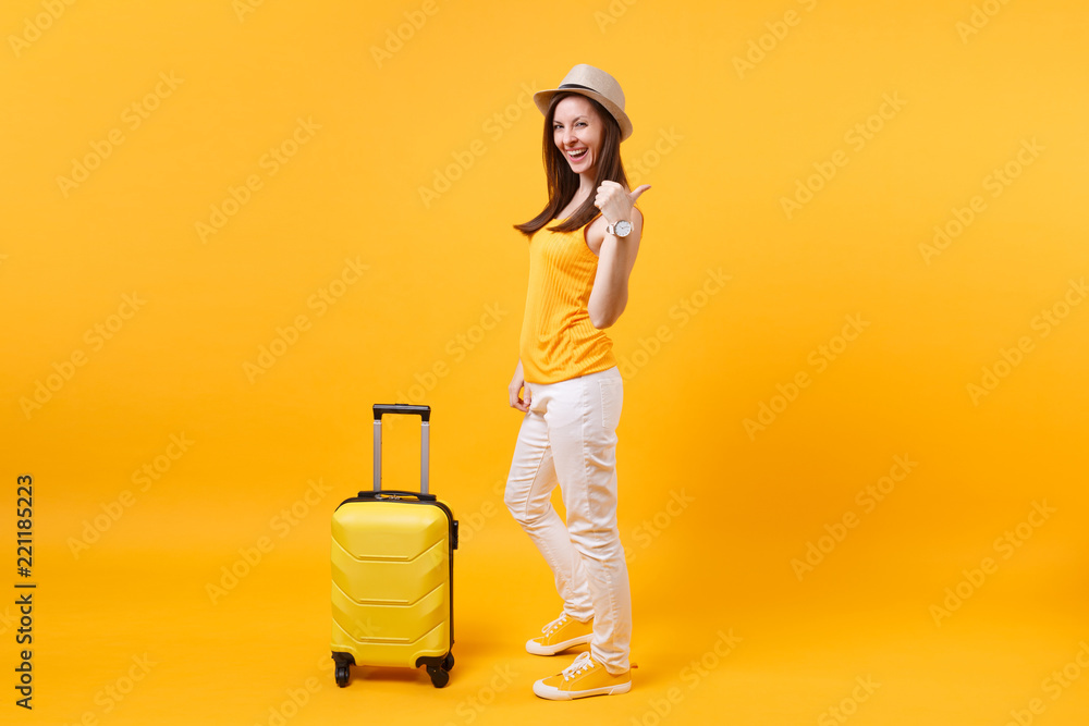 Traveler tourist woman in summer casual clothes, hat with suitcase isolated on yellow orange background. Female passenger traveling abroad to travel on weekends getaway. Air flight journey concept. Traveler tourist woman in summer casual clothes, hat with suitcase isolated on yellow orange background. Female passenger traveling abroad to travel on weekends getaway. Air flight journey concept.