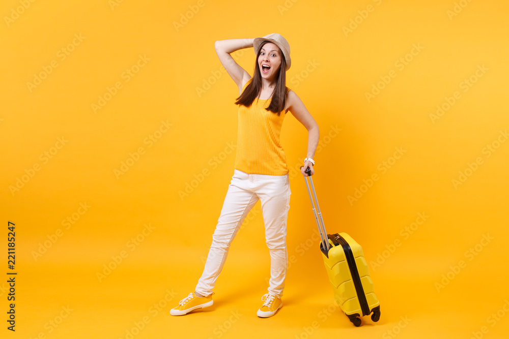 Traveler tourist woman in summer casual clothes, hat with suitcase isolated on yellow orange background. Female passenger traveling abroad to travel on weekends getaway. Air flight journey concept. Traveler tourist woman in summer casual clothes, hat with suitcase isolated on yellow orange background. Female passenger traveling abroad to travel on weekends getaway. Air flight journey concept.