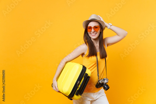 Traveler tourist woman in summer casual clothes, hat with suitcase isolated on yellow orange background. Female passenger traveling abroad to travel on weekends getaway. Air flight journey concept.