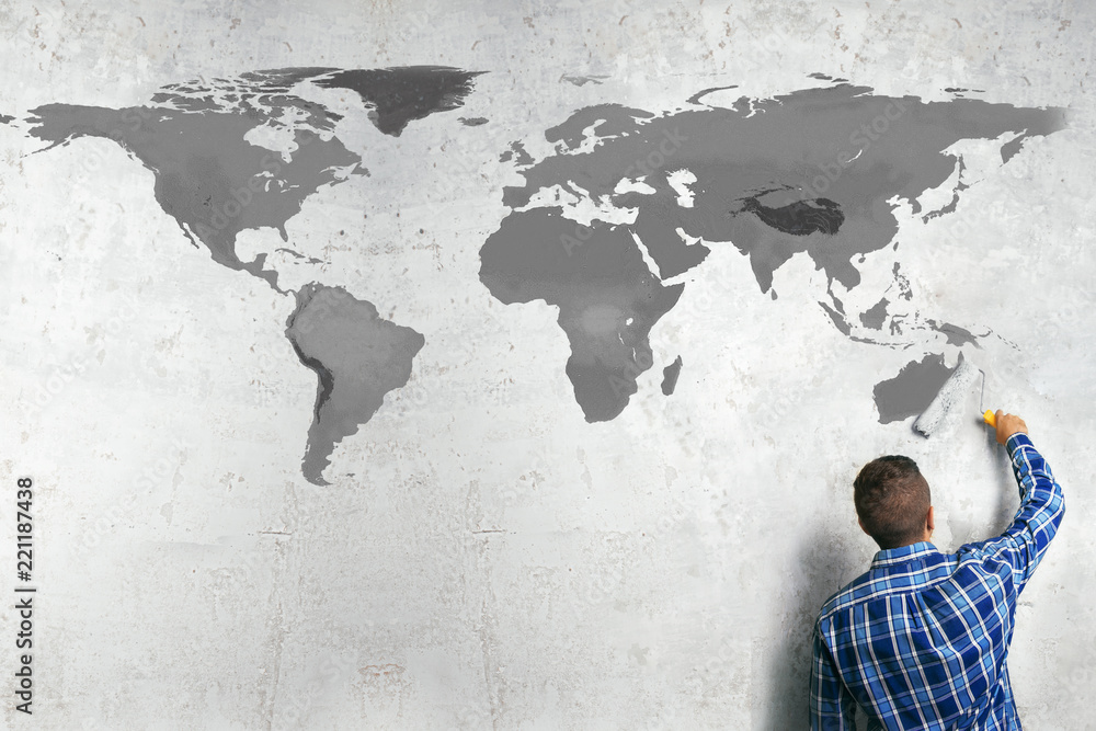 Fototapeta premium A man draws a world map on the wall. Geopolitics concept.