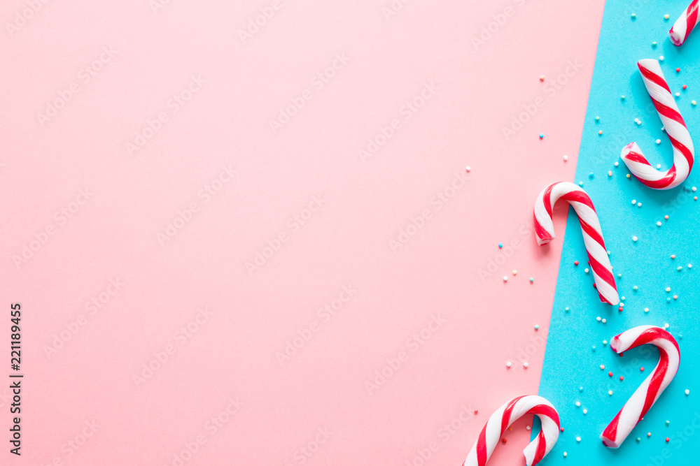 Red and white candy canes on pastel pink and turquoise blue tone paper background. Greeting card. Mockup for positive idea. Empty place for happy, funny cheerful text, quote or sayings.