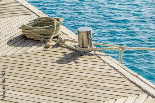 Mooring rope and bollard on sea water and yachts background.