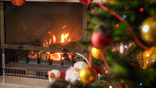 Burning wooden logs in fireplace decorated for Christmas