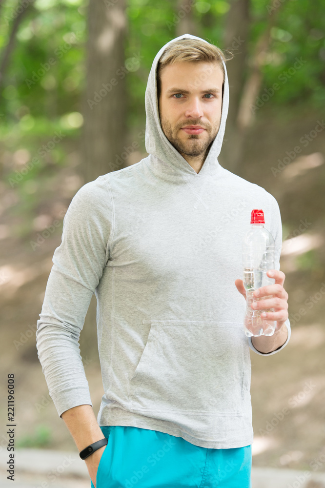 Refreshing vitamin drink after great workout. Man athletic appearance holds water bottle. Athlete drink water after training in park. Man athlete hold bottle care hydration body after workout Refreshing vitamin drink after great workout. Man athletic appearance holds water bottle. Athlete drink water after training in park. Man athlete hold bottle care hydration body after workout