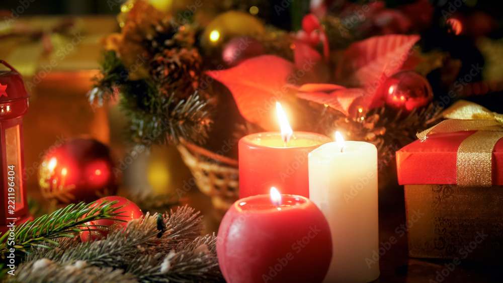 Closeup image of three burning candles and beautiful Christmas wreath on wooden table Closeup image of three burning candles and beautiful Christmas wreath on wooden table